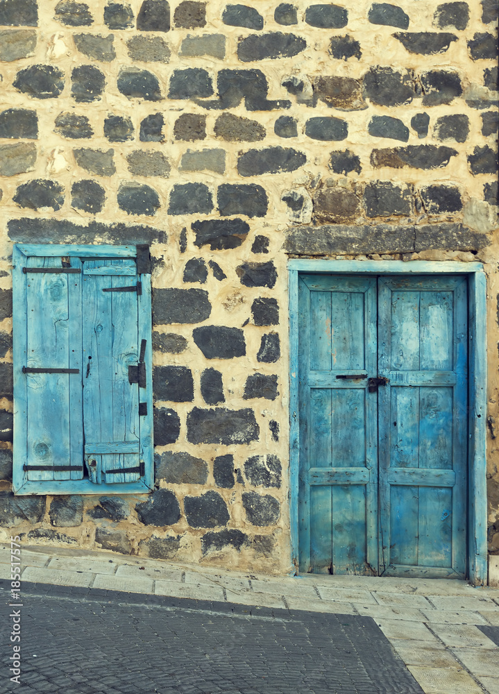 Naklejka premium Old wall with wooden window and worn wooden door.