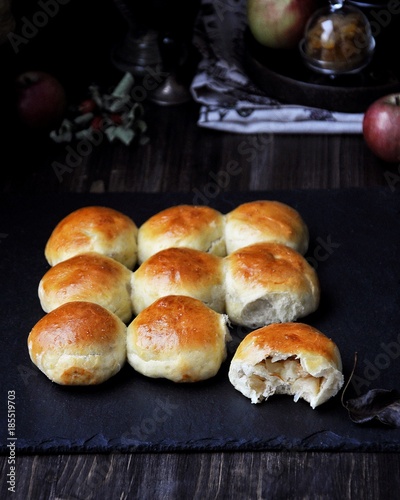 Buns of yeast dough stuffed with apples and raisins. Dark background, fresh apples