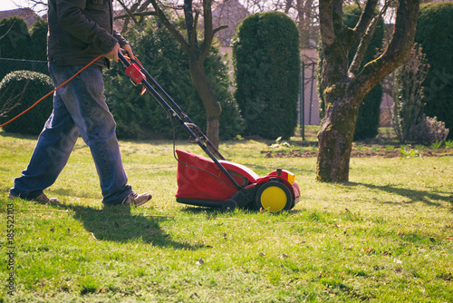 Man with verticutter in the garden, gardener verticutting the lawn at spring, electric lawn raker 