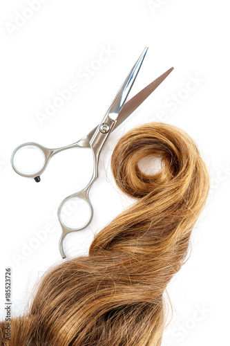 Professional hairdressing scissors and a lock of blond hair.