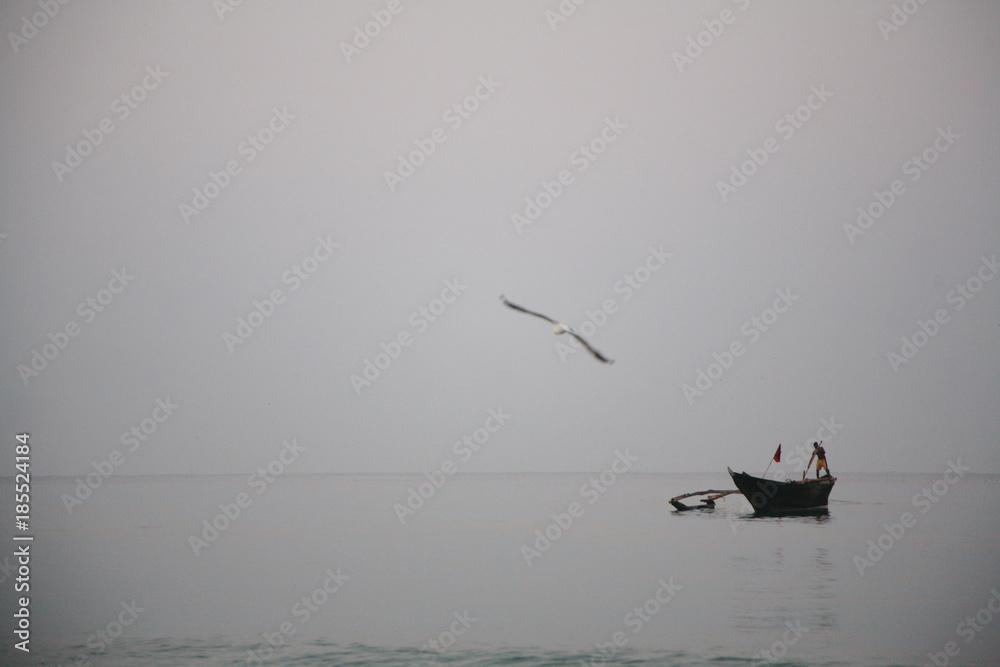 Fototapeta premium Fisherman on an old fishing boat in the calm water of the sea