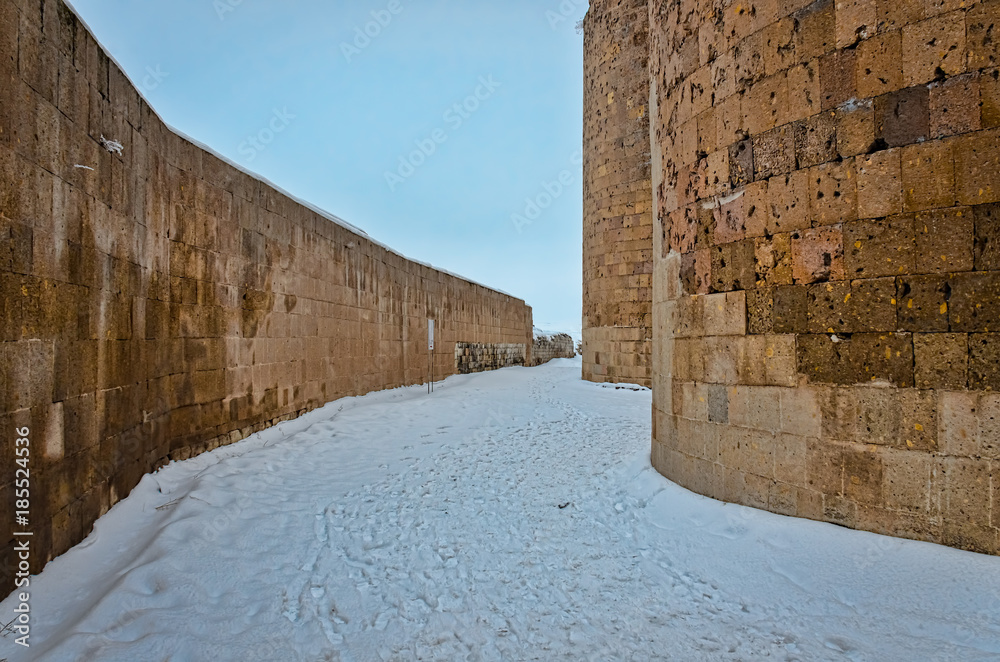 Street covered with snow between the walls of an antique city un