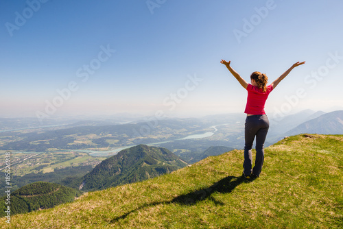 Young female is admiring the view in the mountains with open arms