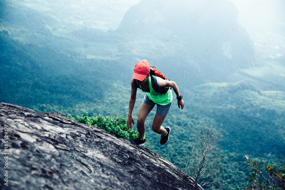 Young fitness woman running up to the mountain top ...
