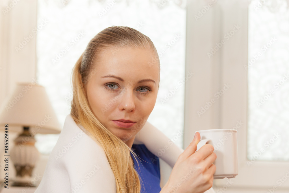 Woman lying on sofa under blanket drinking tea Woman lying on sofa under blanket drinking tea
