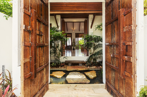 Wooden doors  beautiful Luxury villa Enter with natural decor  stones  water and plants