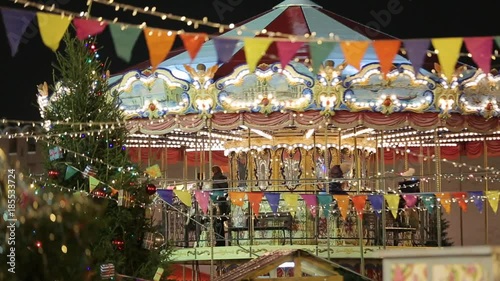 Christmas Fair. Multicolored carousel is spinning in amusement park, colorful illuminated carousel with colorful lights, Holiday. Night time
