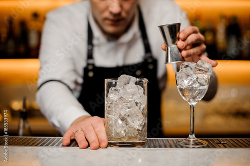 Bartender dressed in a white shirt with a glass with ice cubes
