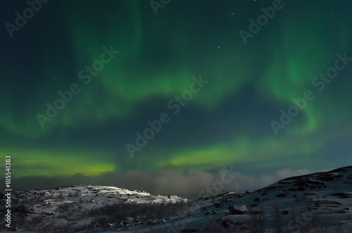 Northern lights, aurora over hills and tundra in the winter.