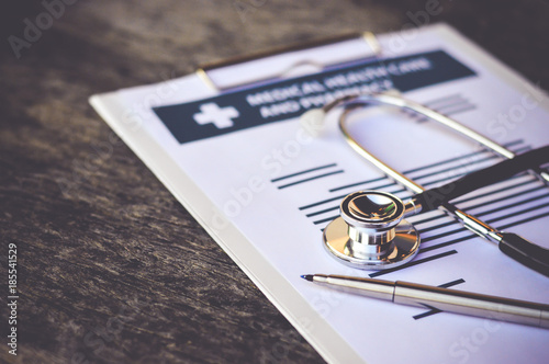 Stethoscope and pen on report pad ,health and medical concept ,selective focus.