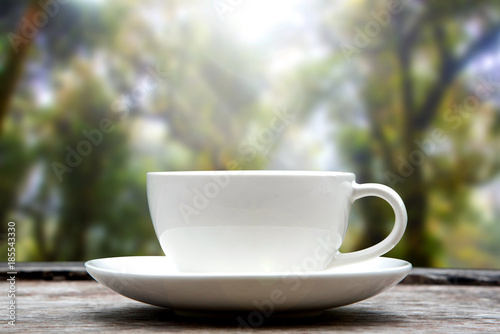 Hot coffee cup on wood table nature blurred background.