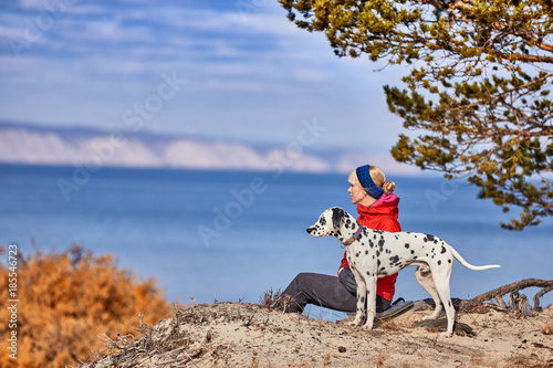 Dark clouds gathering over lake Baikal. A girl and a dog are walking along the coast.