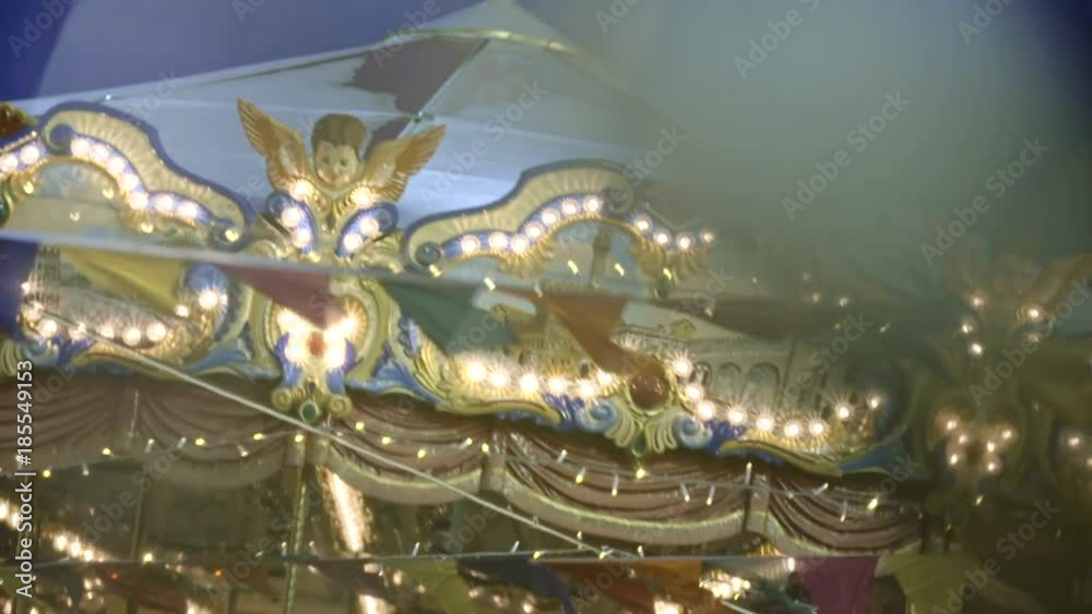 Beautiful illuminated merry-go-round details while rounding at Christmas fair in slow motion. Vintage colorful wooden horse on the top of a carousel. Holidays and Christmas mood concept. Beautiful illuminated merry-go-round details while rounding at Christmas fair in slow motion. Vintage colorful wooden horse on the top of a carousel. Holidays and Christmas mood concept.