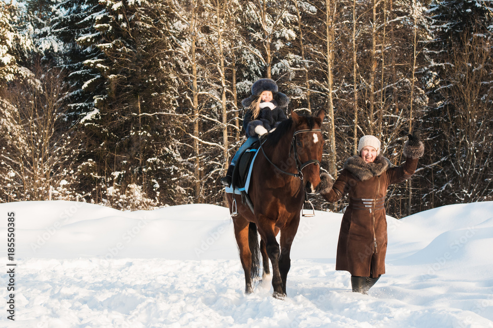 Small girl and mom near horse in a winter Small girl and mom near horse in a winter