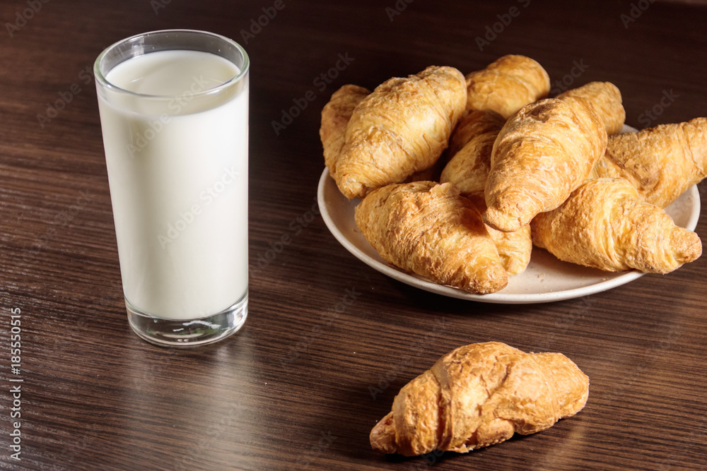Glass of milk and fresh croissants on wooden table Glass of milk and fresh croissants on wooden table