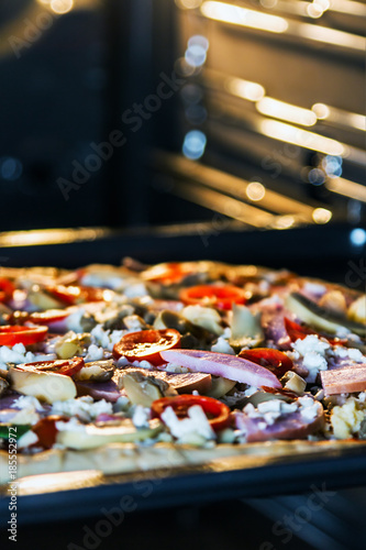 pizza with mushrooms, ham and mozzarella cooked baking in the oven