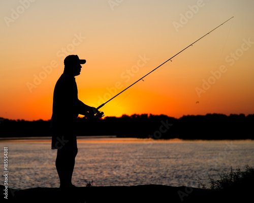 Silhouette of a man with a fishing rod at sunset
