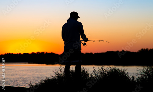 Silhouette of a man with a fishing rod at sunset
