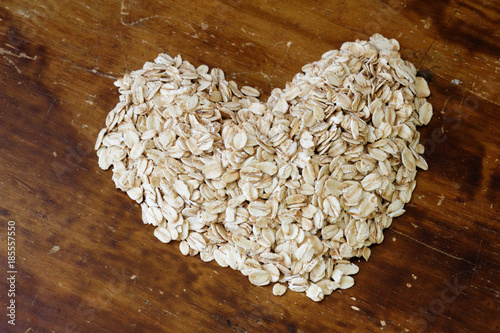 Fitness and health concept. Heart shape oat on wooden background photo