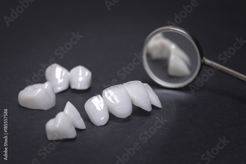 Dental mirror and zircon dentures on a dark background - Ceramic veneers - lumineers photo