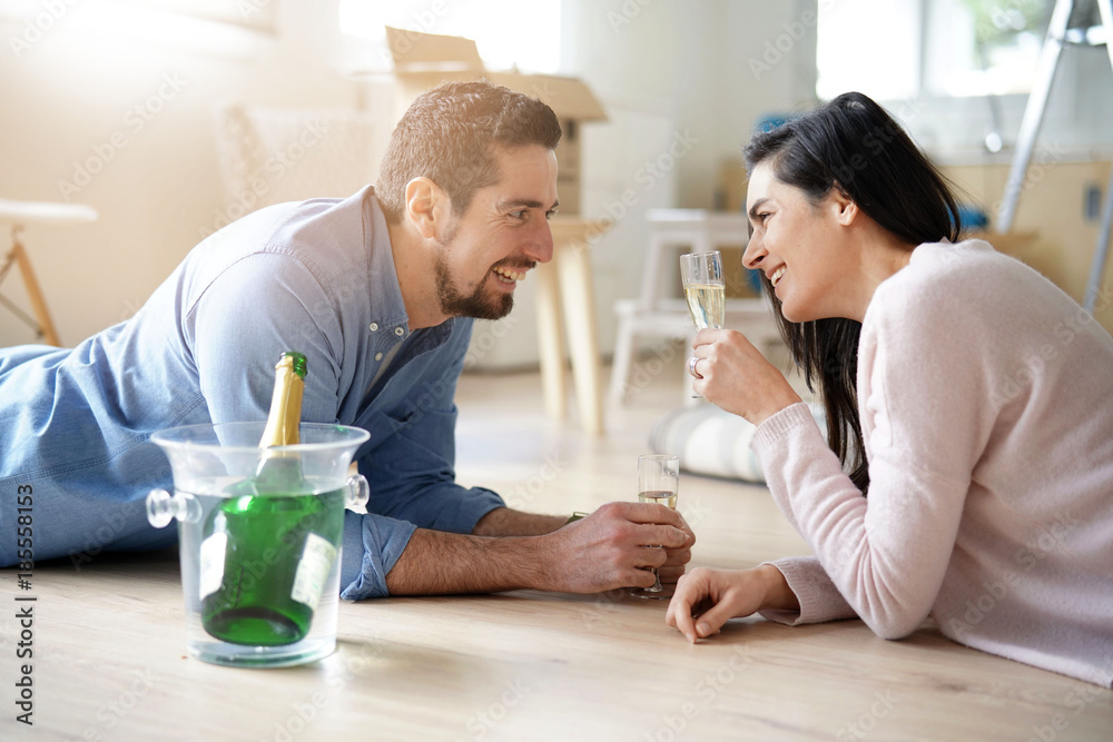 Couple cheering with champagne in new home