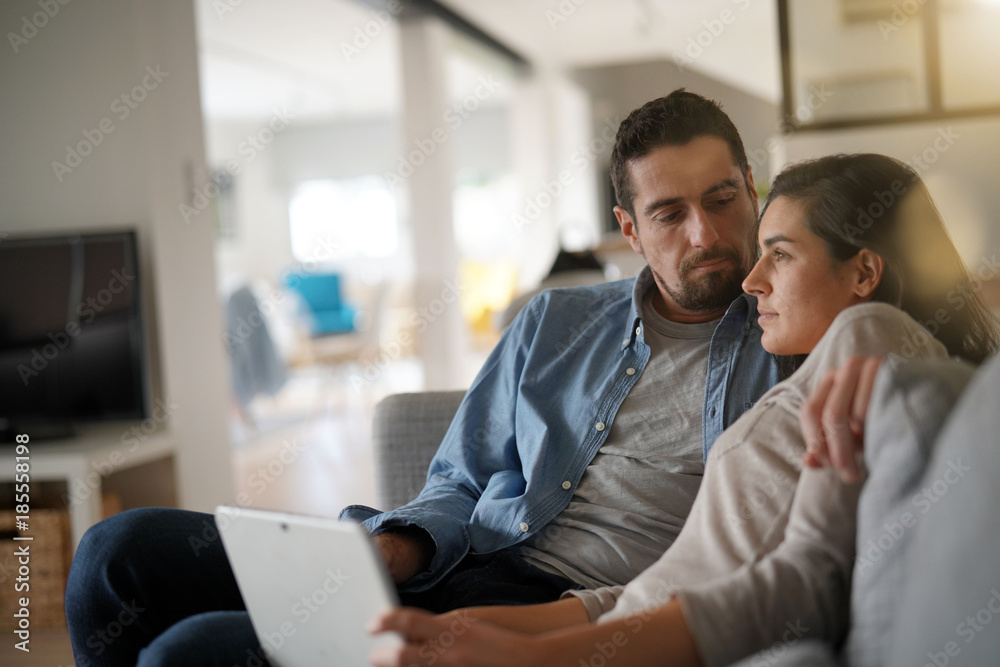 Fototapeta premium Couple relaxing in sofa and connected with digital tablet
