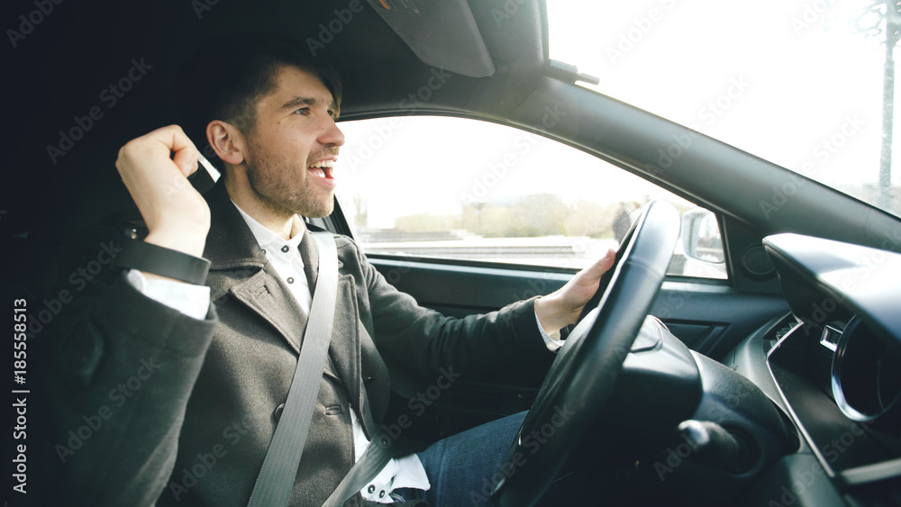 Happy handsome businessman driving car and singing. Man is happy after making deals and drives home Happy handsome businessman driving car and singing. Man is happy after making deals and drives home