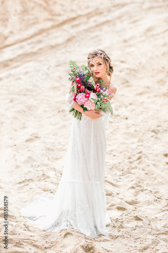 Beautiful bride alone on the sand. The bride in a wedding dress.