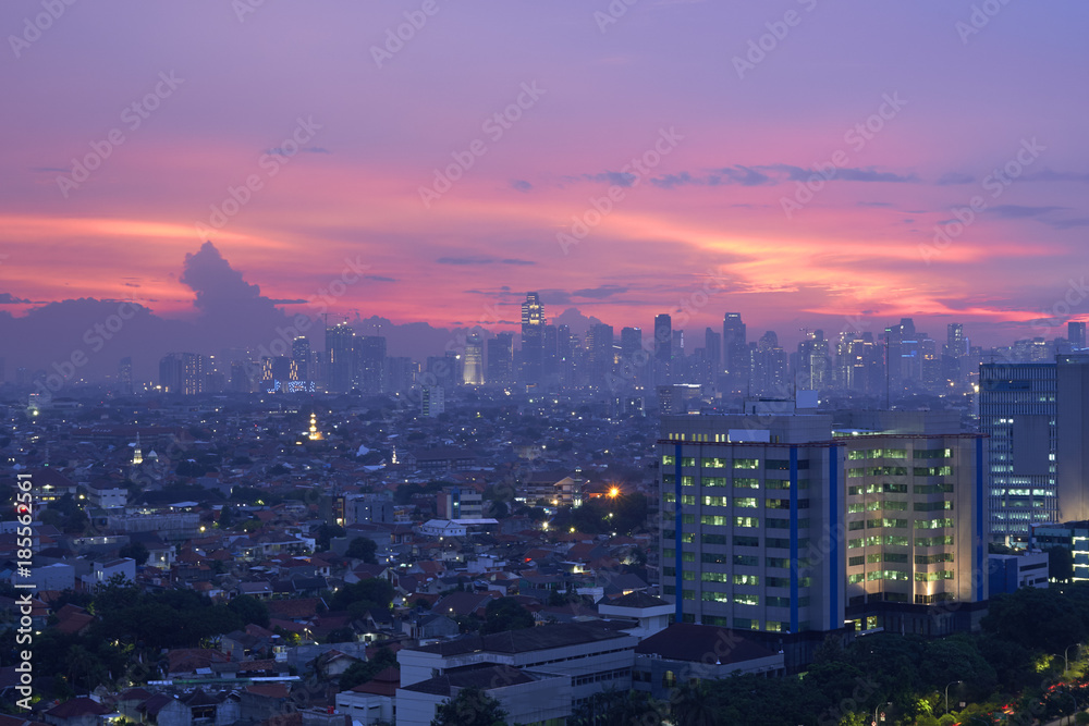 The scenery of Jakarta city in the evening with the sparkling lights of buildings and houses of residents, decorated with a reddish sky.