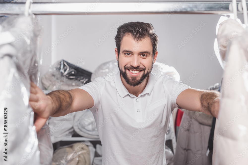Obraz premium dry cleaning worker at warehouse with clothing packed in plastic bags