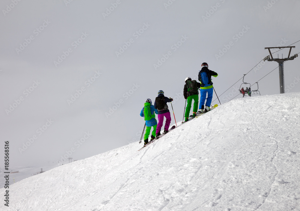 Skiers on snowy off-piste slope and overcast misty sky