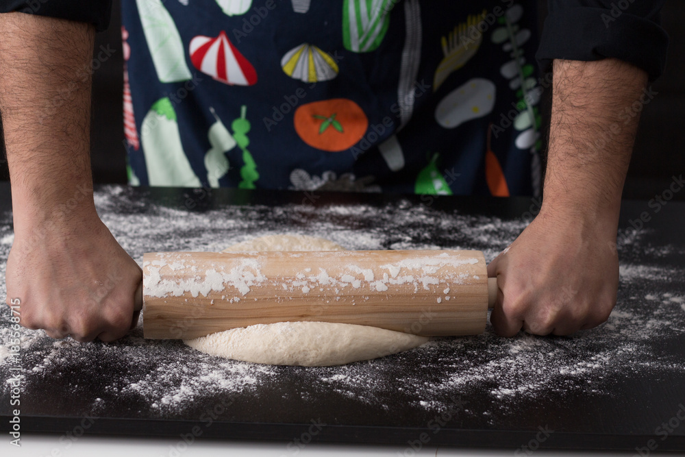 Male hands rolling dough, baking preparation closeup.