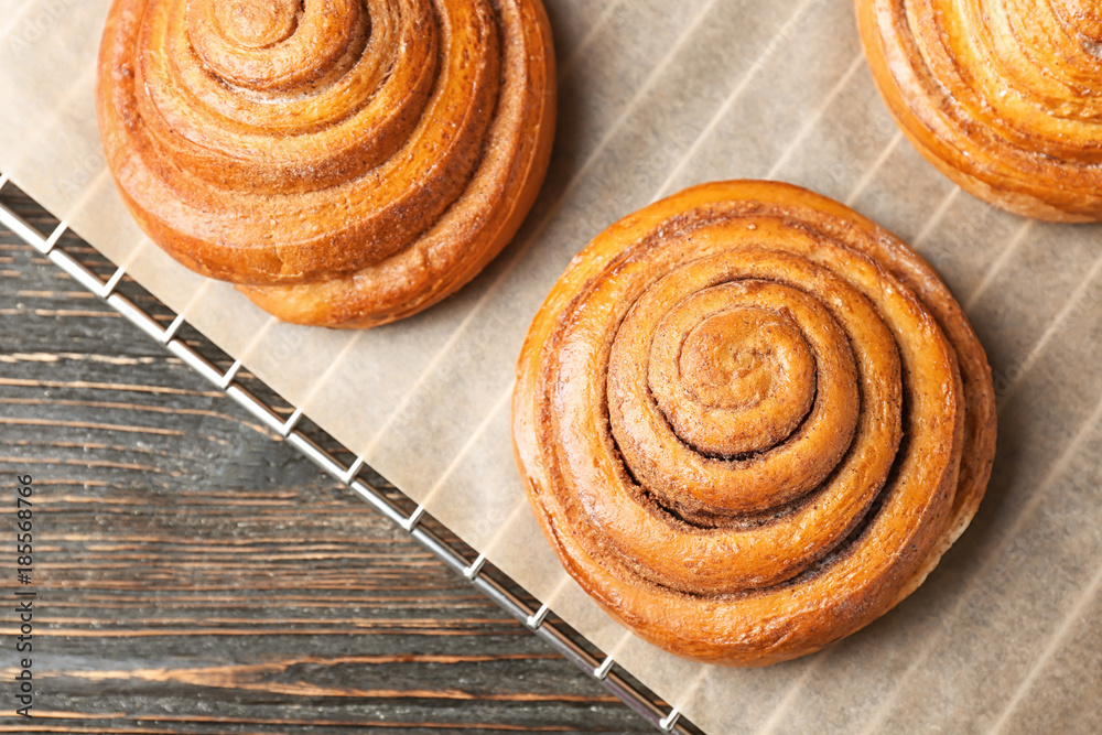 Fototapeta premium Cooling rack with sweet cinnamon rolls on table