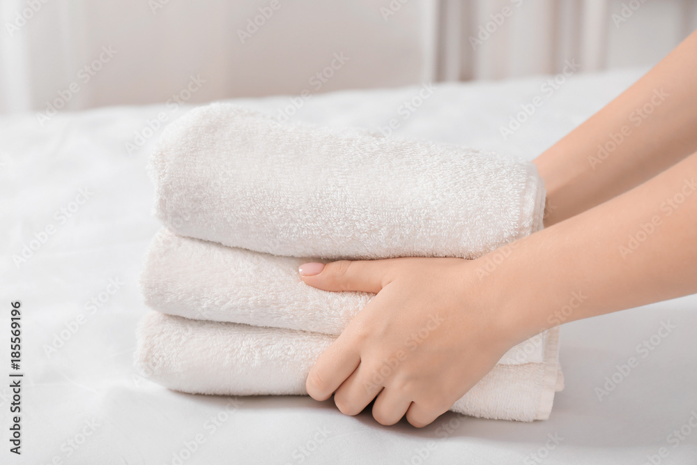 Woman putting stack of towels on bed Woman putting stack of towels on bed