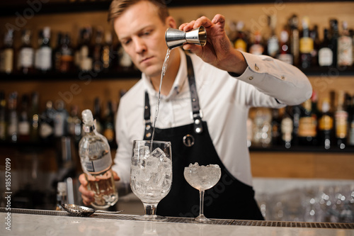 Barman pouring a portion of vodka into a glass
