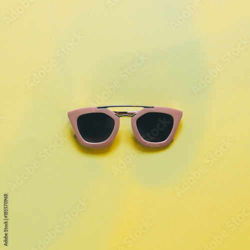 pink sunglasses for woman on yellow background. flat lay. minimal.