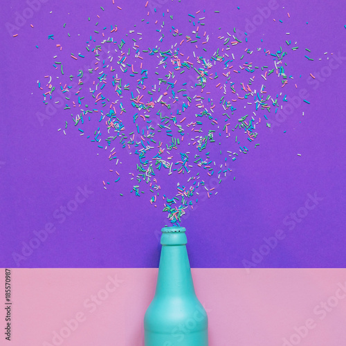 Blue champagne bottle with confetti glittering splashes. minimal holiday drink. flat lay