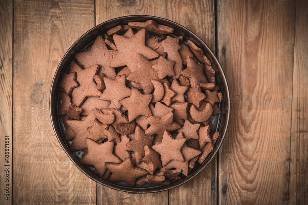Christmas gingerbread cakes in shape of stars gathered in springform bowl on rustic wooden table.