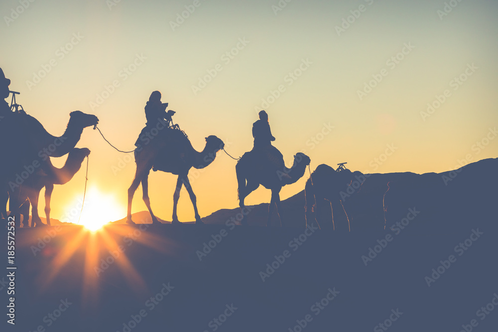 Camel caravan with people going through the sand dunes in the Sahara Desert. Morocco, Africa. Camel caravan with people going through the sand dunes in the Sahara Desert. Morocco, Africa.