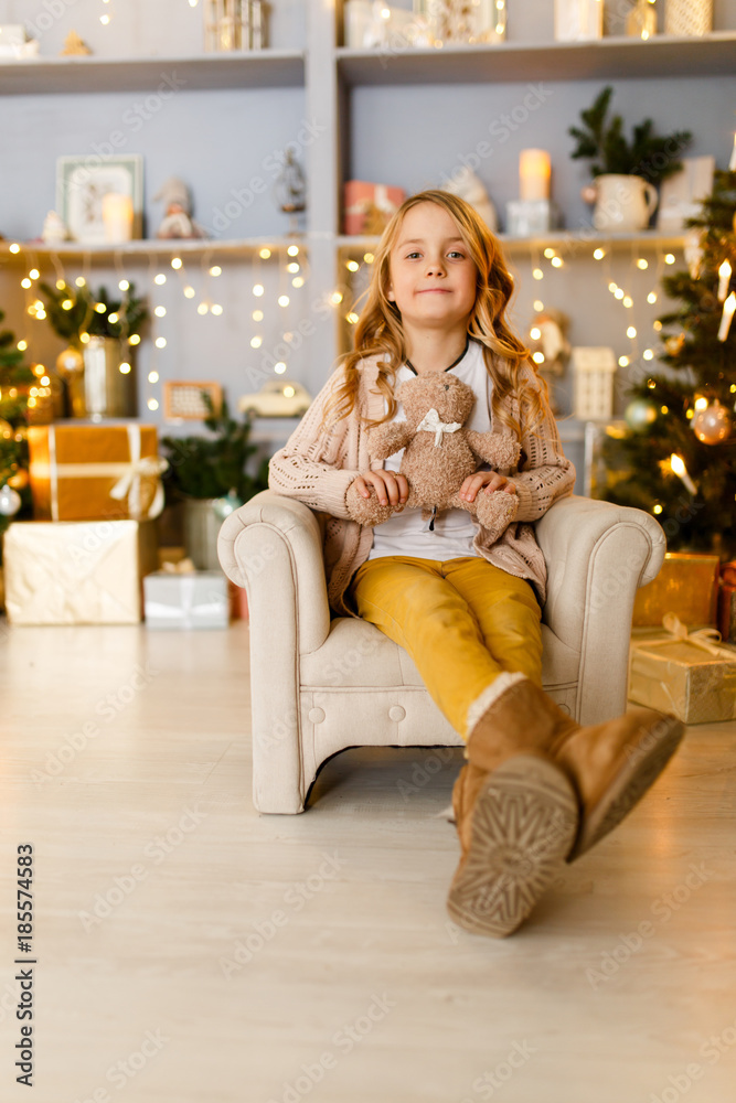 Photo of girl sitting in chair on background of Christmas decorations Photo of girl sitting in chair on background of Christmas decorations