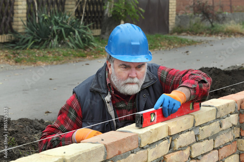 Worker control brick wall using level tool, real people, no retouch