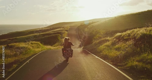Couple on vintage motorcycle riding into the sunset photo