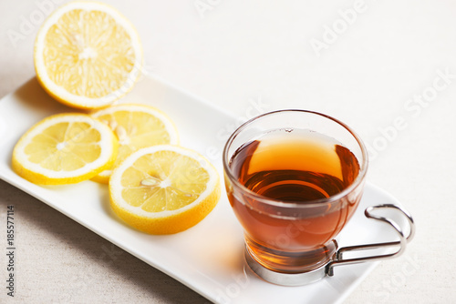 Tea cup with lemon on white plate. Infusion.
