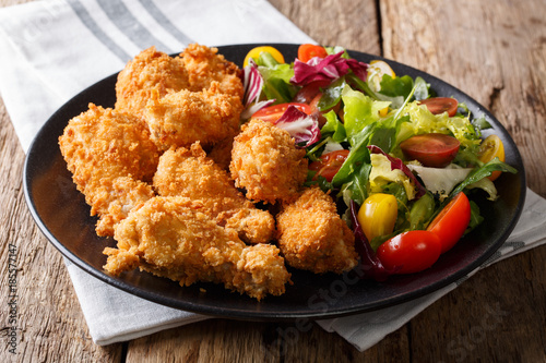 Fried chicken wings in breadcrumbs and fresh vegetable salad close-up. horizontal