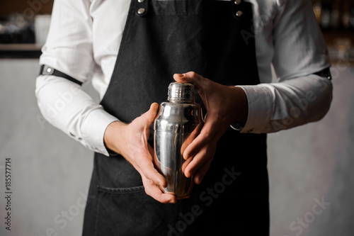 Bartenders hands holding a shaker against the bar counter