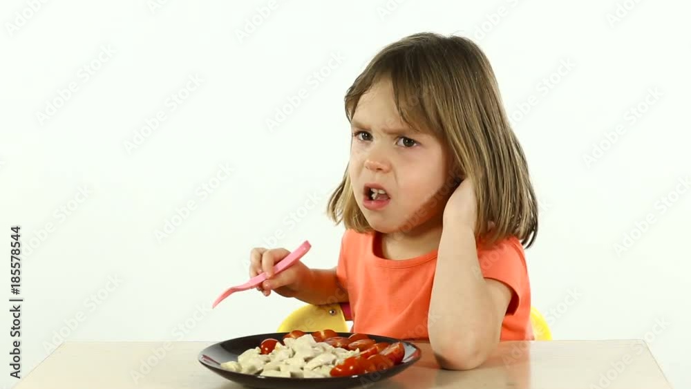 A child eats food unwillingly. Girl 4-5 years old, portrait on a white background. A child eats food unwillingly. Girl 4-5 years old, portrait on a white background.