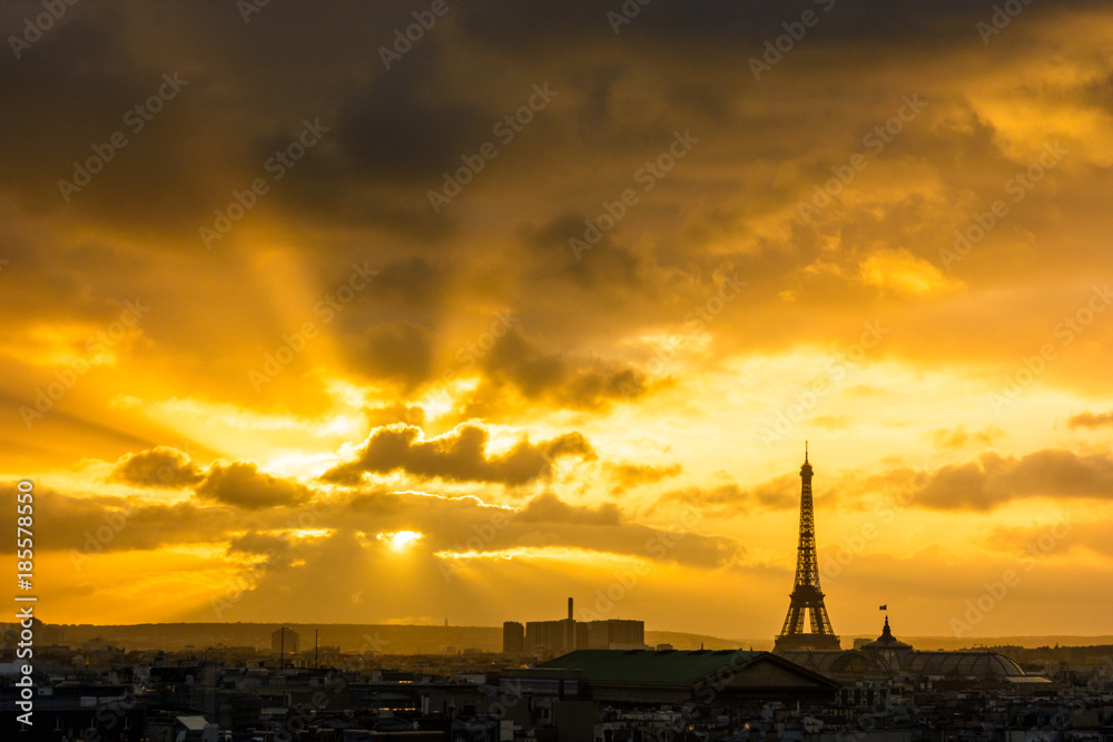 Cityscape of a blazing sunset over Paris skyline with the silhouette of the Eiffel tower standing out against the red stormy sky.