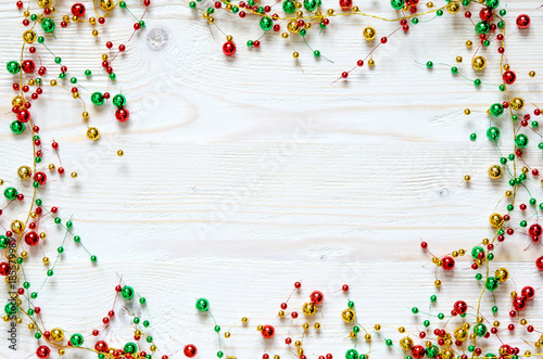 Frame from a Christmas colorful garland on a white wooden surface.  