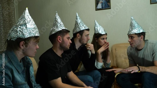 Friends in foil on the head of the house. Gathering of friends about listening to their ideas of extraterrestrial civilizations
