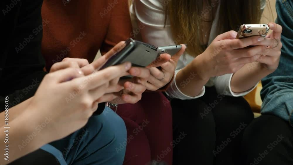 Closeup of friends chatting on mobile phone in network. Group of friends are using gadgets during recreation time at home. Friends sitting and chatting in the phone closeup